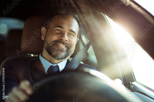 Smiling businessman driving car during sunny day photo