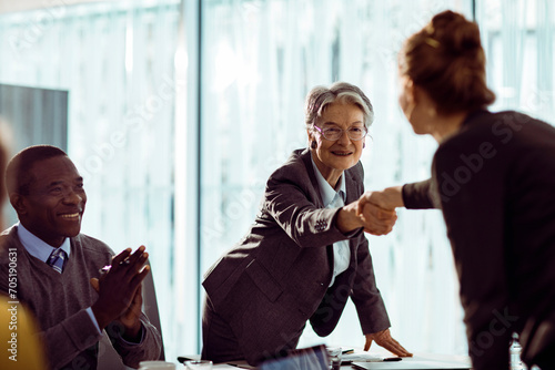 Senior businesswoman shaking hands with colleague during office meeting photo