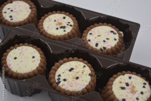 Delicious branded, factory-made, chocolate chip cookies with white fudge, fruit, chocolate pieces arranged on a white background. Biscuits are in a brown, pretty package.