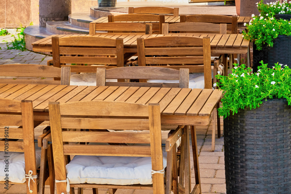 wooden furniture, tables and chairs of a cozy outdoor cafe on a clear sunny summer day. beautiful postcard for the designer. desktop background wooden furniture, tables and chairs of a cozy outdoor cafe on a clear sunny summer day. beautiful postcard for the designer. desktop background