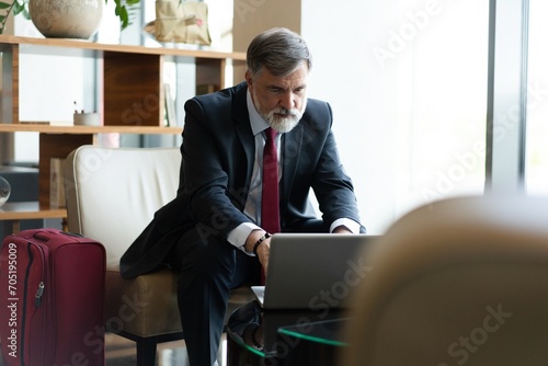 Businessman looking busy working on laptop. Thoughtful business professional reading emails on laptop in office lobby