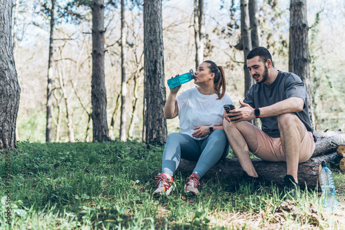 Canvastavla Sitting on a fallen tree trunk, the couple, including the determined overweight female, catch their breath, their laughter blending with the rustling leaves as they enjoy a post-workout moment