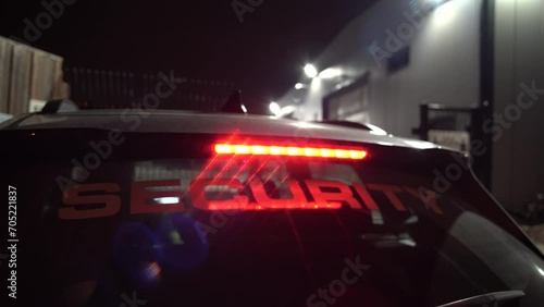 A security car is stationed at the entrance of a commercial facility at night to watch out for car theft. 