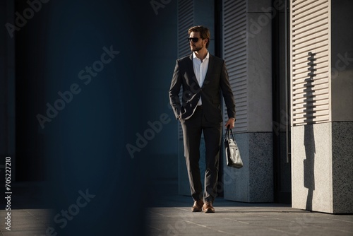 Elegant handsome man in classic suit standing near the office building.