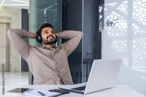 Photography Close-up photo of a young Indian man sitting in an office at a desk and resting