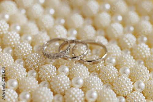 Three golden rings, one diamond-studded, rest on white pearls. Symbolizes a church engagement. The serene, elegant image evokes love and commitment