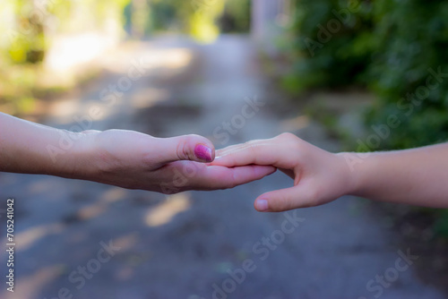 Close up view of mother and daughter holding their hands in the public park. Mothers love © Jelena
