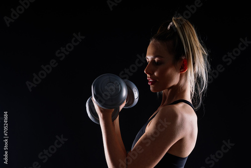 Athletic woman in sportswear raises dumbbells leads healthy lifestyle has happy expression