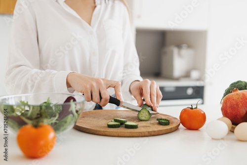 A happy cute blonde woman is preparing a salad in the kitchen