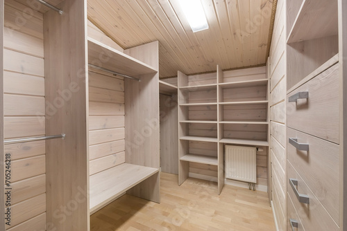 Dressing room decorated with light wood. Spacious cabinets, shelves and storage boxes.
