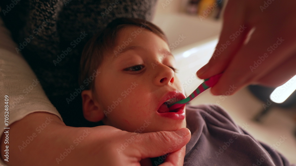 Closeup child's face while mother brushes teeth, dental hygiene night routine before bed, young boy's mouth during dental hygiene Closeup child's face while mother brushes teeth, dental hygiene night routine before bed, young boy's mouth during dental hygiene