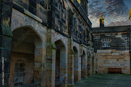 Historic stone building with archways under a dramatic sky at dusk in Lancaster. © Vas