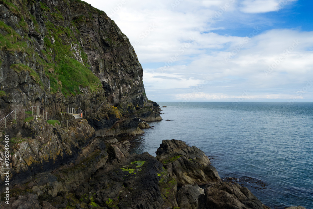 Fototapeta premium Felsen beim Klippenpfad Gobbins Cliff mit Wolken