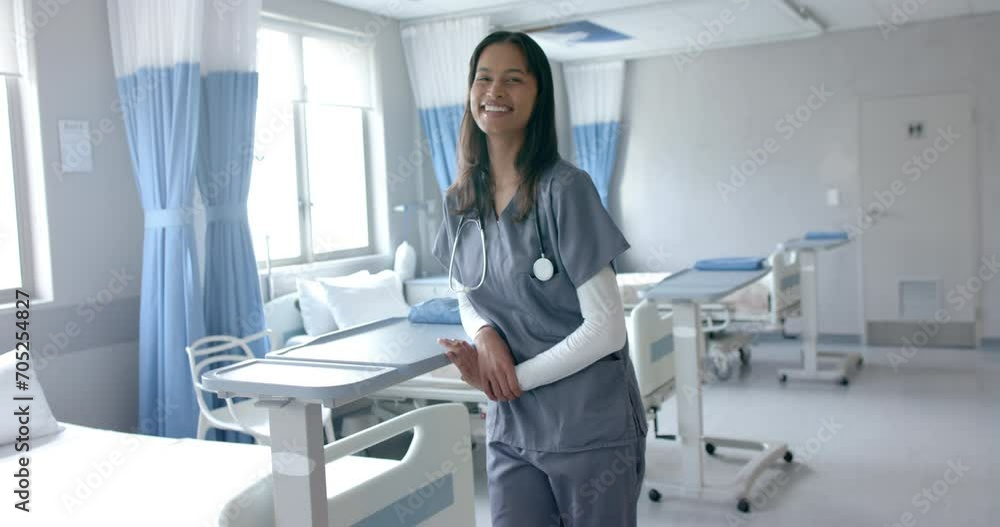 Portrait of happy biracial female doctor in scrubs smiling in hospital ward, copy space, slow motion Portrait of happy biracial female doctor in scrubs smiling in hospital ward, copy space, slow motion