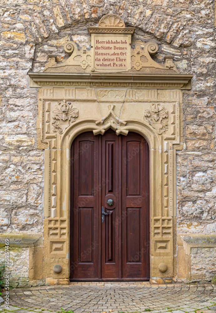 Stone surround with decorative elements and bible inscription in german language on the entrance door at sebastianskirche in Kochendorf, Bad Friedrichshall in southern germany