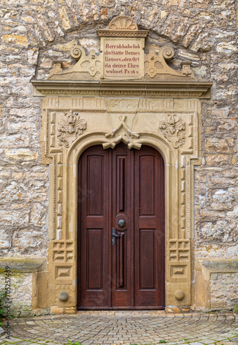 Stone surround with decorative elements and bible inscription in german language on the entrance door at sebastianskirche in Kochendorf, Bad Friedrichshall in southern germany © Jens Hertel