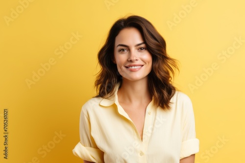 portrait of smiling young woman looking at camera isolated on yellow background