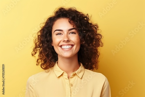 Portrait of a happy smiling young woman with curly hair over yellow background © Igor