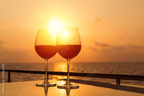 Glasses, red wine and tropical sunset with sea background, nobody. © photopixel