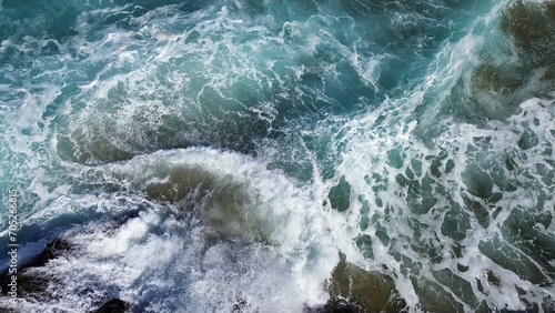 Aerial view of a tranquil beach scene featuring a body of blue water lapping against rocks