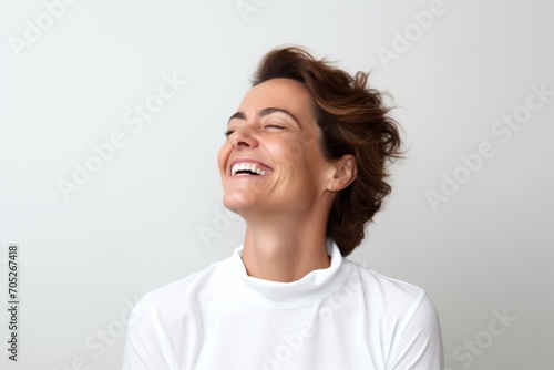 Portrait of a happy young woman laughing and looking up over gray background