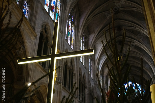 A modern cross with LEDs illuminates the interior of a dark European church.