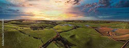 Fotografi Panoramic view of a lush countryside at sunset with vibrant skies and rolling hills