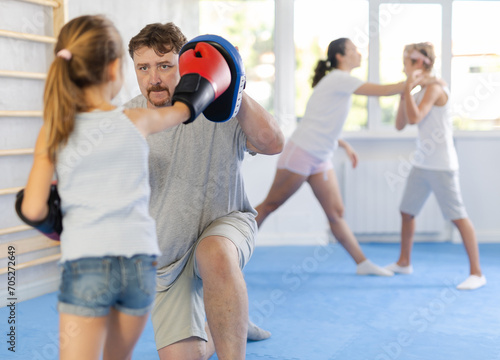Young girl hitting the focus mitts held by his boxing father