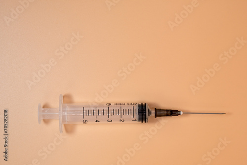 Empty 5ml syringe with needle on peach background. Copy Space. photo