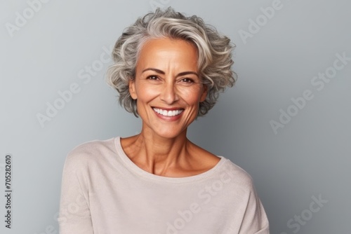 Portrait of a happy senior woman looking at camera over grey background