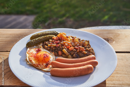 Boiled pork sausages served with sunny side up egg, pickled sweet and sour cucumbers and lentil mash with roasted onion on the top. Simple and healthy dish with balanced nutritions from eastern europe