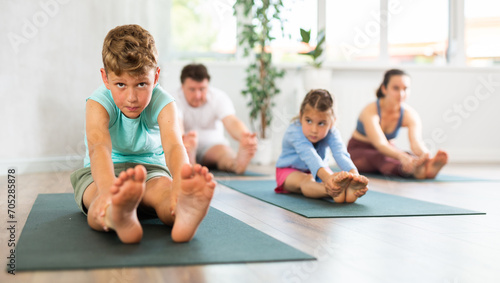 Little boy with parents and brother doing yoga in fitness class