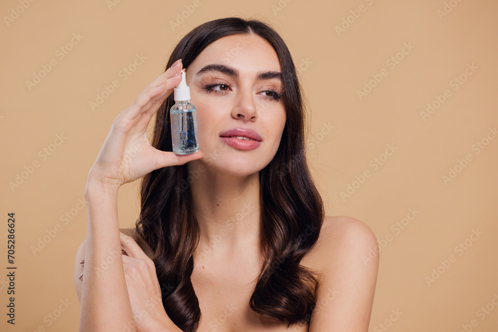Fototapeta premium Woman Dropping Serum on Face on Beige Background