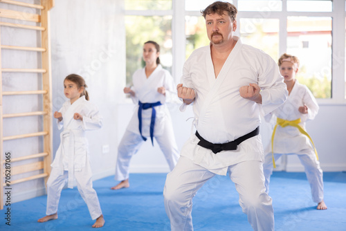 Parents with children athletes starting position and studying repeating sequence of punches and painful techniques in karate kata technique. Oriental martial arts, training and obtaining black belt