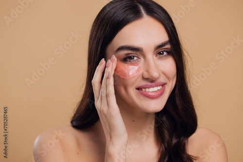Beauty portrait of happy woman applying pink hydro gel pathches on her eyes