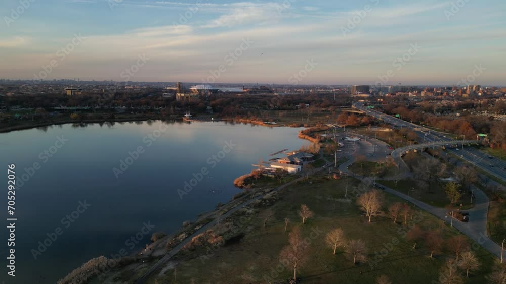 flying towards tennis stadium (corona flushing meadows park center) meadow lake at dusk, sunset with cars driving on road (aerial drone footage from above) flying towards tennis stadium (corona flushing meadows park center) meadow lake at dusk, sunset with cars driving on road (aerial drone footage from above)
