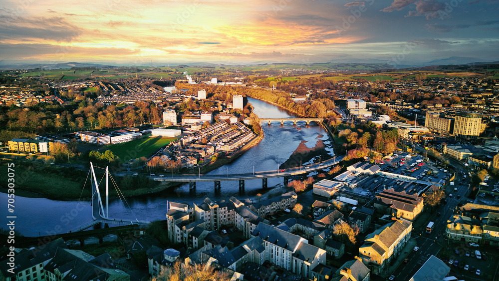 Aerial view of a city Lancaster at sunset with a river, bridges, and warm lighting.