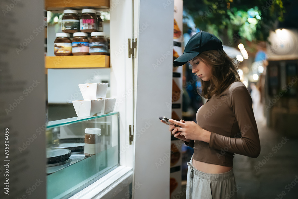Teenage girl is waiting for her street food to be prepared. Teenage girl is waiting for her street food to be prepared.