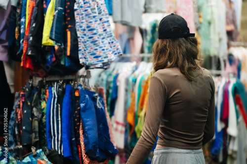 Teenage girl choosing a clothes at the evening bazaar. © M-Production