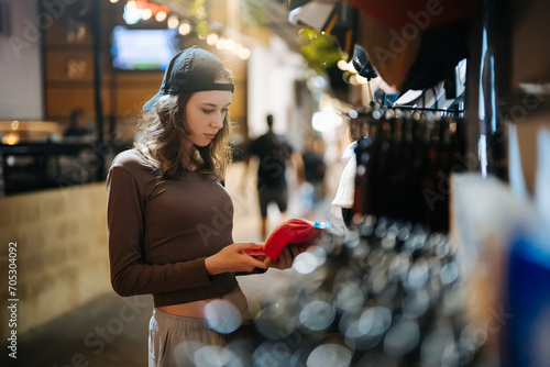 Teenage girl choosing a cap for herself.