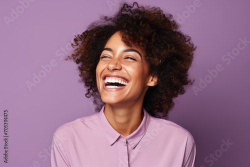 Portrait of happy young african american woman laughing against purple background