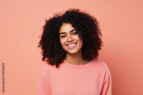 Portrait of a beautiful young african american woman smiling against pink background