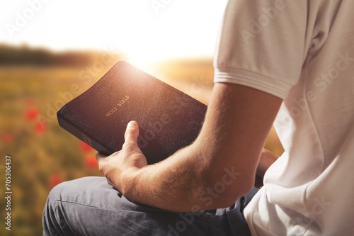 Person reading book praying with Bible photo