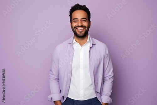 Portrait of a handsome young arabic man looking at camera and smiling while standing against purple background