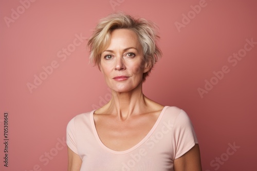 Portrait of beautiful middle aged woman with short blond hair over pink background.