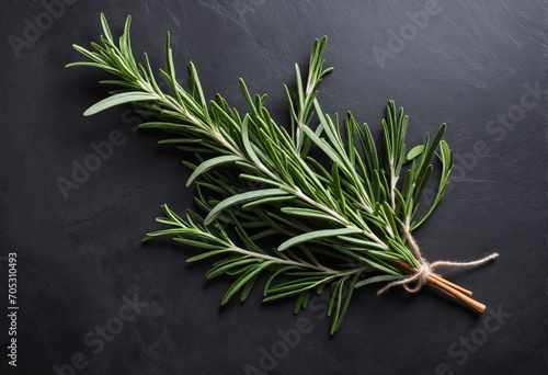 Top view of rosemary on a dark concrete table with various herbs and spices in the background. Plenty of space for writing your recipes.