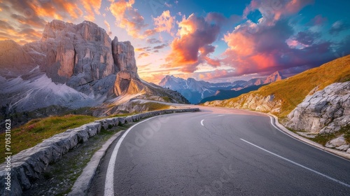 Mountain road at colorful sunset in summer. Dolomites, Italy. Beautiful curved roadway, rocks, stones, blue sky with clouds. Landscape with empty highway through the mountain pass in spring. Travel photo
