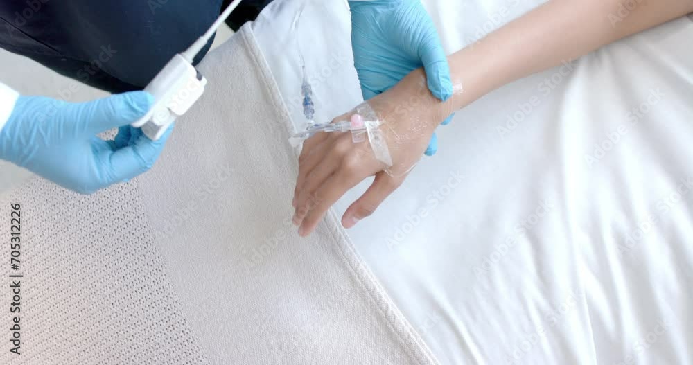 Male doctor in putting oximeter on finger of biracial female patient in bed, copy space, slow motion Male doctor in putting oximeter on finger of biracial female patient in bed, copy space, slow motion