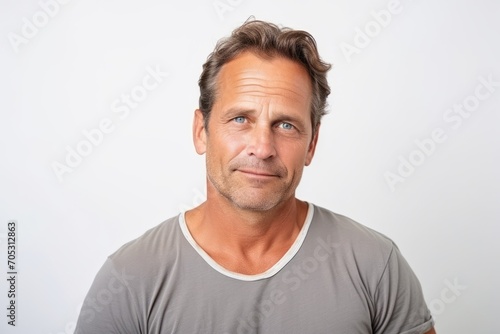 Portrait of a handsome mature man looking at camera while standing against grey background