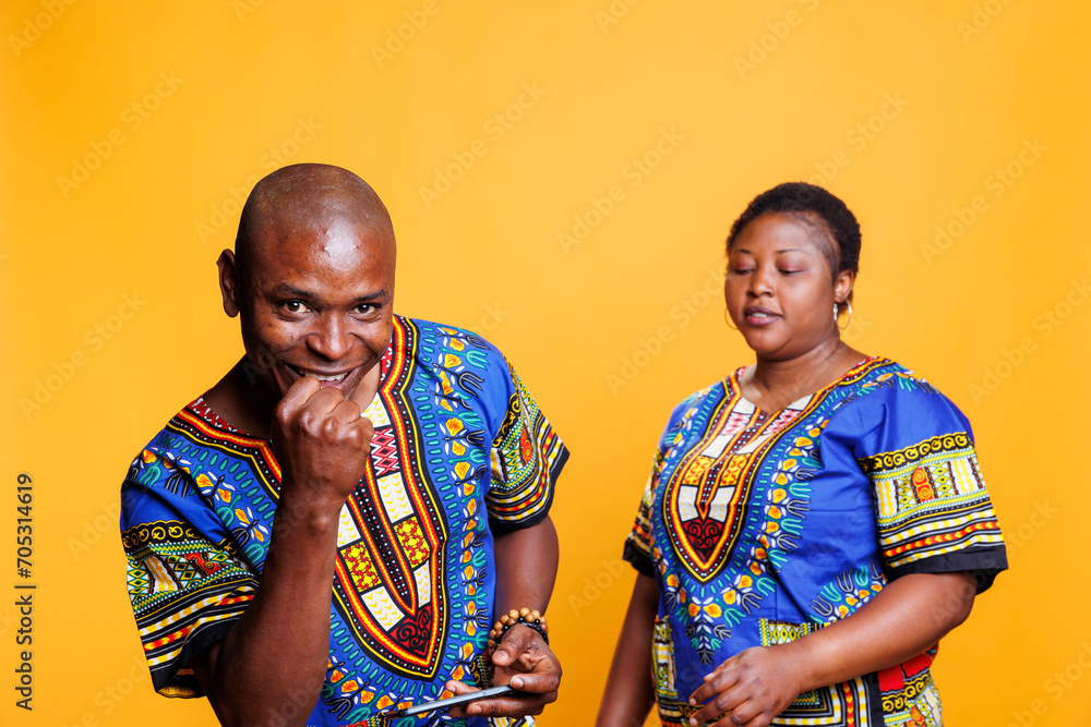 Obraz premium Happy man showing winner gesture and celebrating success while playing mobile game with wife. Mid adult boyfriend showing winner clenched fist while disappointed girlfriend loosing competition